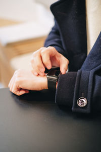 Midsection of person using smart watch on table