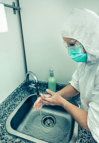 Side view of doctor washing hands in sink