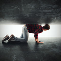 Side view of young man lying on wall at home