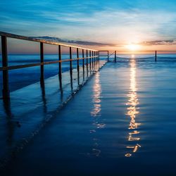 Railing on sea against sky during sunset