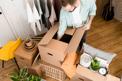 Mature man unpacking things from boxes while moving in new apartment.