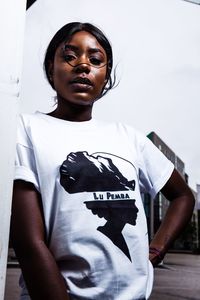 Portrait of young woman standing against wall