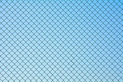 Full frame shot of chainlink fence against blue sky