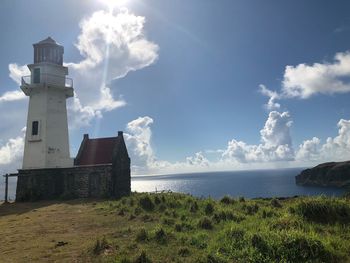 Lighthouse amidst sea and buildings against sky