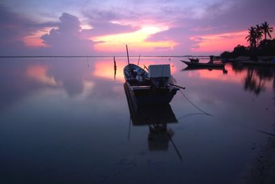 Boat moored on sea against sky during sunset