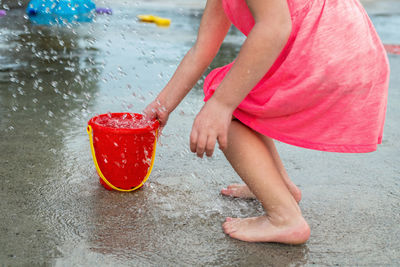Little child playing with water and toys at splash pad playground in park 