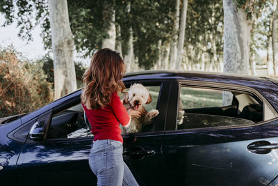 Rear view of woman with dog on car
