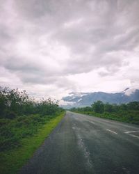 Road by trees against sky