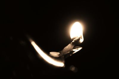 Close-up of illuminated candle against black background