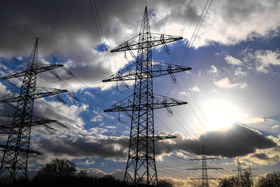 Low angle view of electricity pylon against sky during sunset