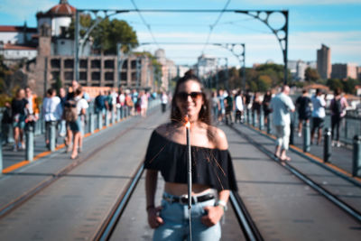 Young woman with illuminated sparkler standing on railroad tracks in city