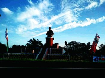 Silhouette man standing by road against sky in city