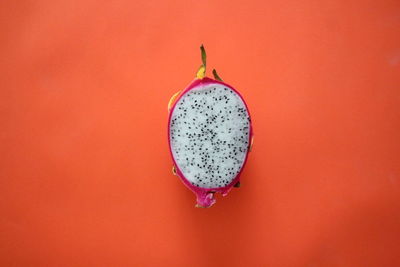 Close-up of red hanging against orange wall