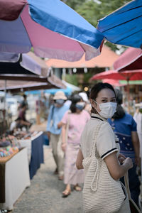 Young women wear surgical protection mask and carrying reusable bag walking in street market