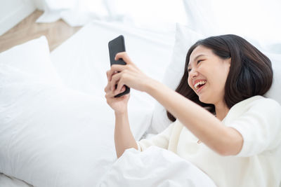 Young woman using mobile phone on bed