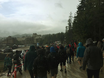 Rear view of people walking in city during rainy season