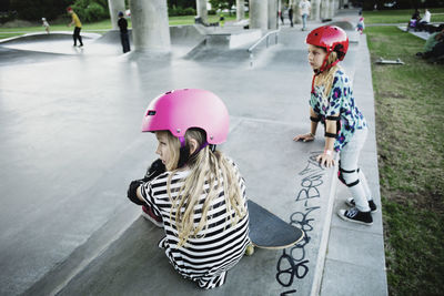 Friends looking away while resting at skateboard park