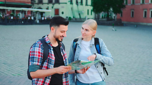 Portrait of young woman using mobile phone while standing in city