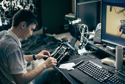 A young man repairs the engine steering wheel on a joystick.