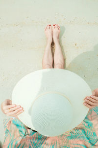 Woman wearing hat while sitting on sand at beach