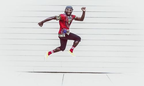 Full length of woman jumping against wall