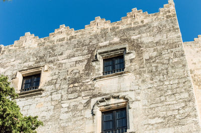 Low angle view of old building against clear blue sky