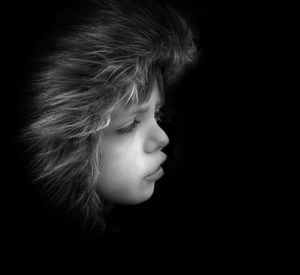 Portrait of girl looking away against black background