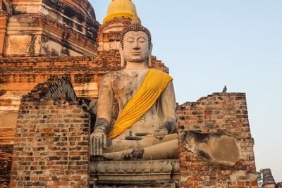 Low angle view of statue against historic building against sky