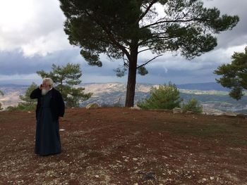 Woman standing by tree against sky