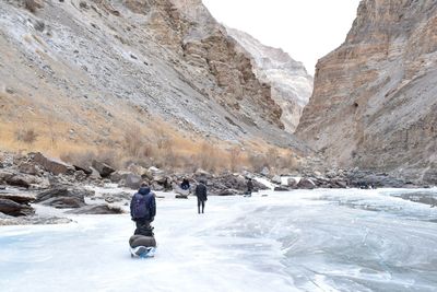 Rear view of people walking on snow covered mountain