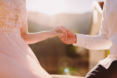 Midsection of bride and groom holding hands