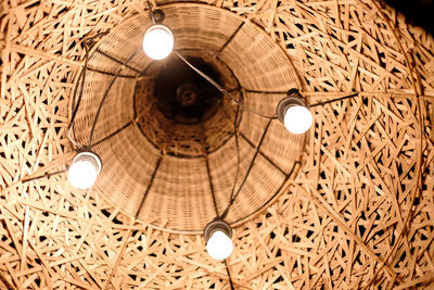 Low angle view of illuminated light bulb hanging from ceiling