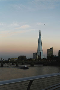 River in city against sky during sunset