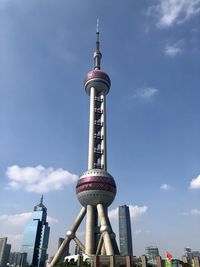 Low angle view of communications tower in city against sky