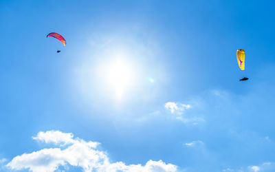 Low angle view of paragliding against blue sky