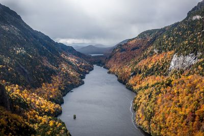 Scenic view of river amidst mountains against sky during autumn