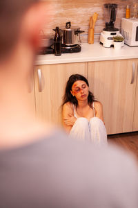 Portrait of young woman sitting on bed at home