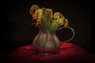 Close-up of flower vase on table against black background