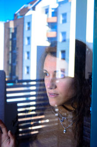 Portrait of woman looking through window