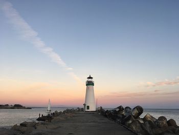Lighthouse on beach against sky during sunset