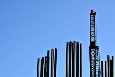 Low angle view of crane against clear blue sky