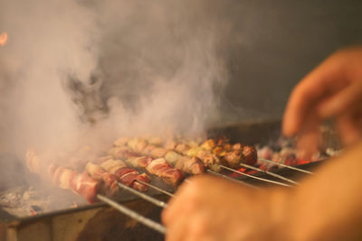 Cropped hand grilling meat on barbecue