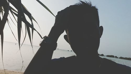 Rear view of silhouette man photographing sea against clear sky