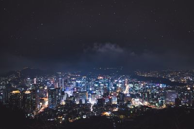 Illuminated cityscape against star field sky at night