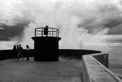 People standing by sea against sky