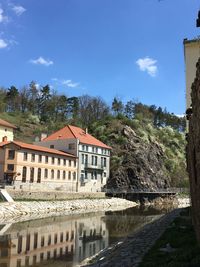 Buildings by river against blue sky