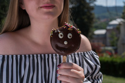 Midsection of woman eating chocolate candy during summer