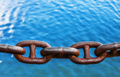 Close-up of rusty chain over sea
