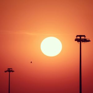 Silhouette street light against orange sky