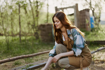 Young woman using mobile phone while sitting on field